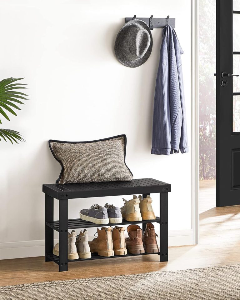 Black bamboo shoe rack bench with footwear on two shelves beside an entry door
