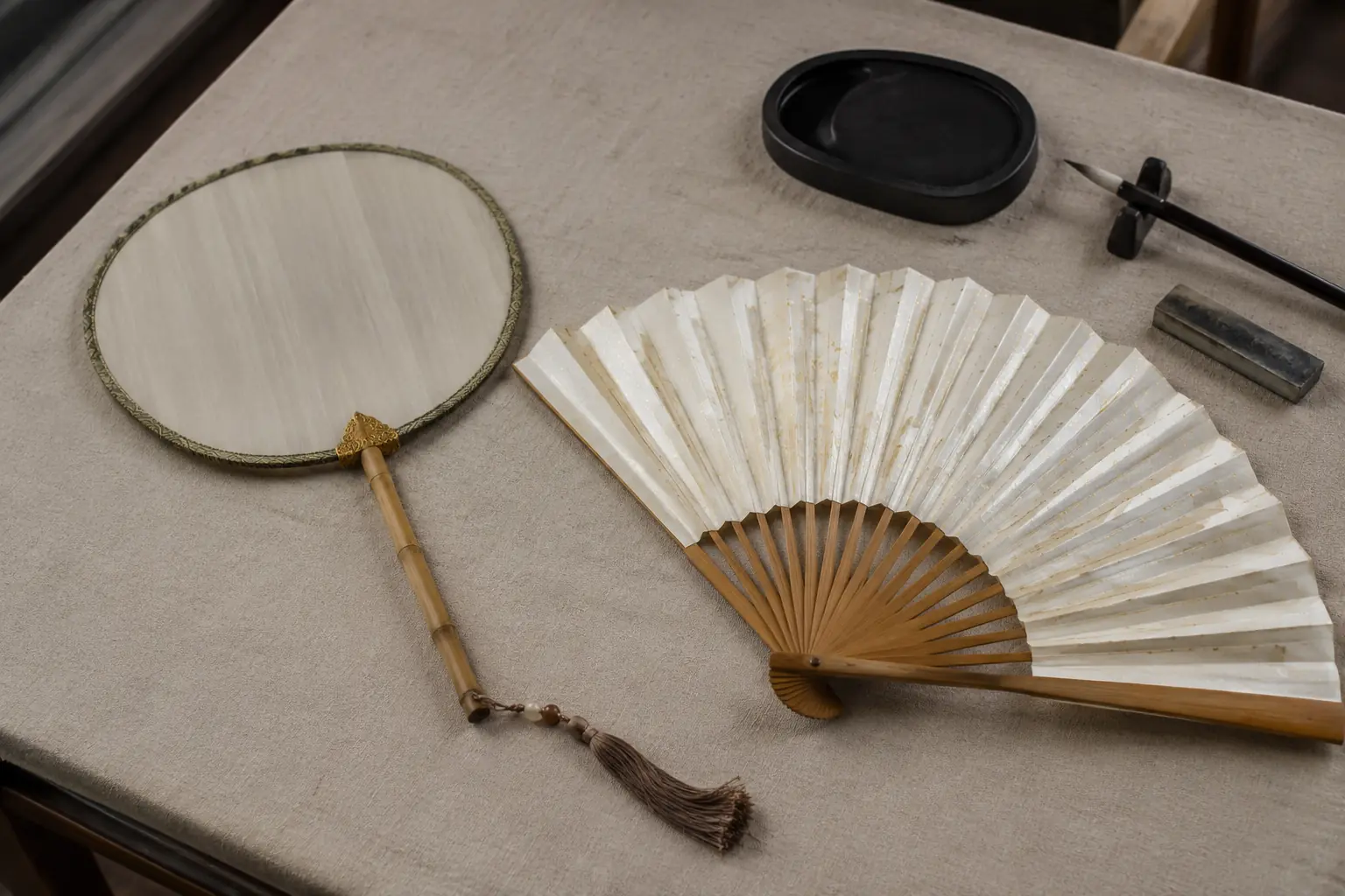Chinese rigid round fan and folding bamboo fan displayed on a worktable