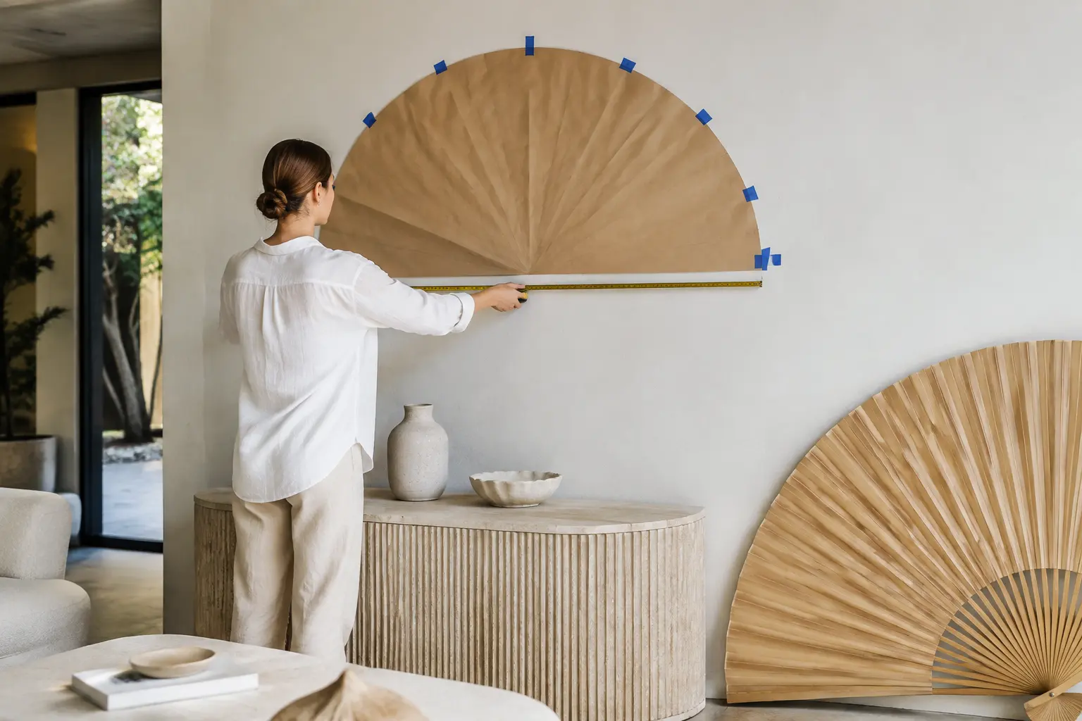 Designer measuring a wall with a full-size template for an oversized bamboo fan