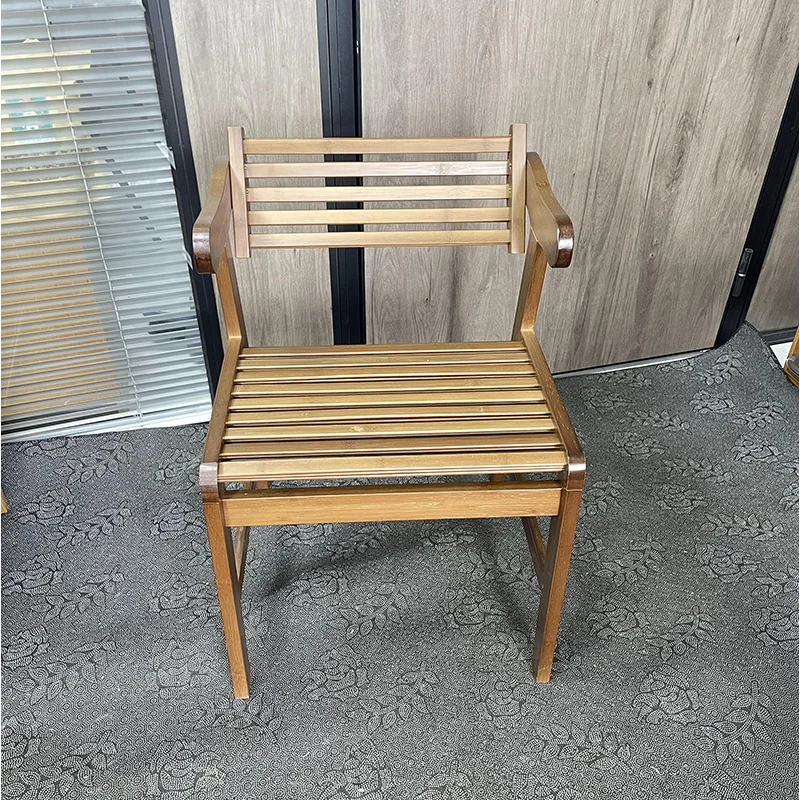 Front view of a bamboo arm dining chair with an open slatted seat and back in a warm brown finish.