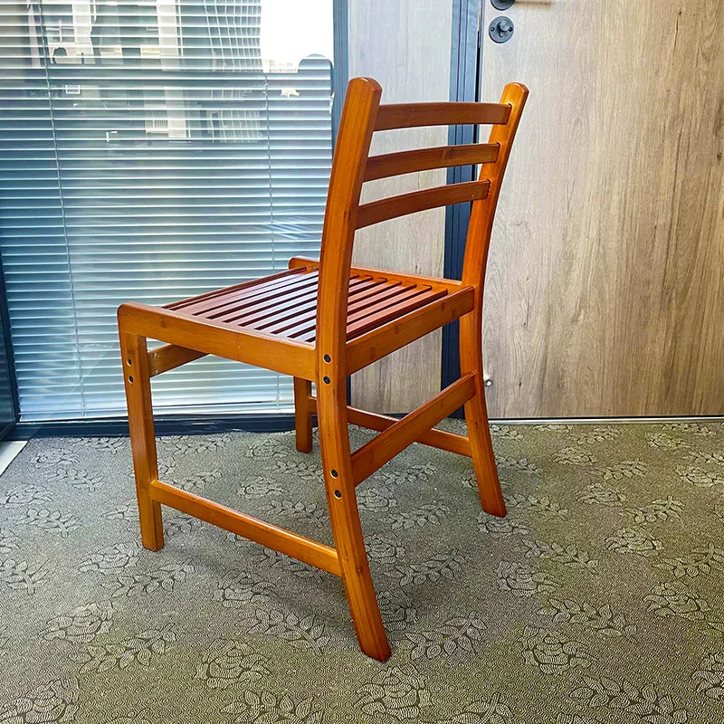 Rear three-quarter view of a bamboo dining chair showing its ladder back and reinforced frame.