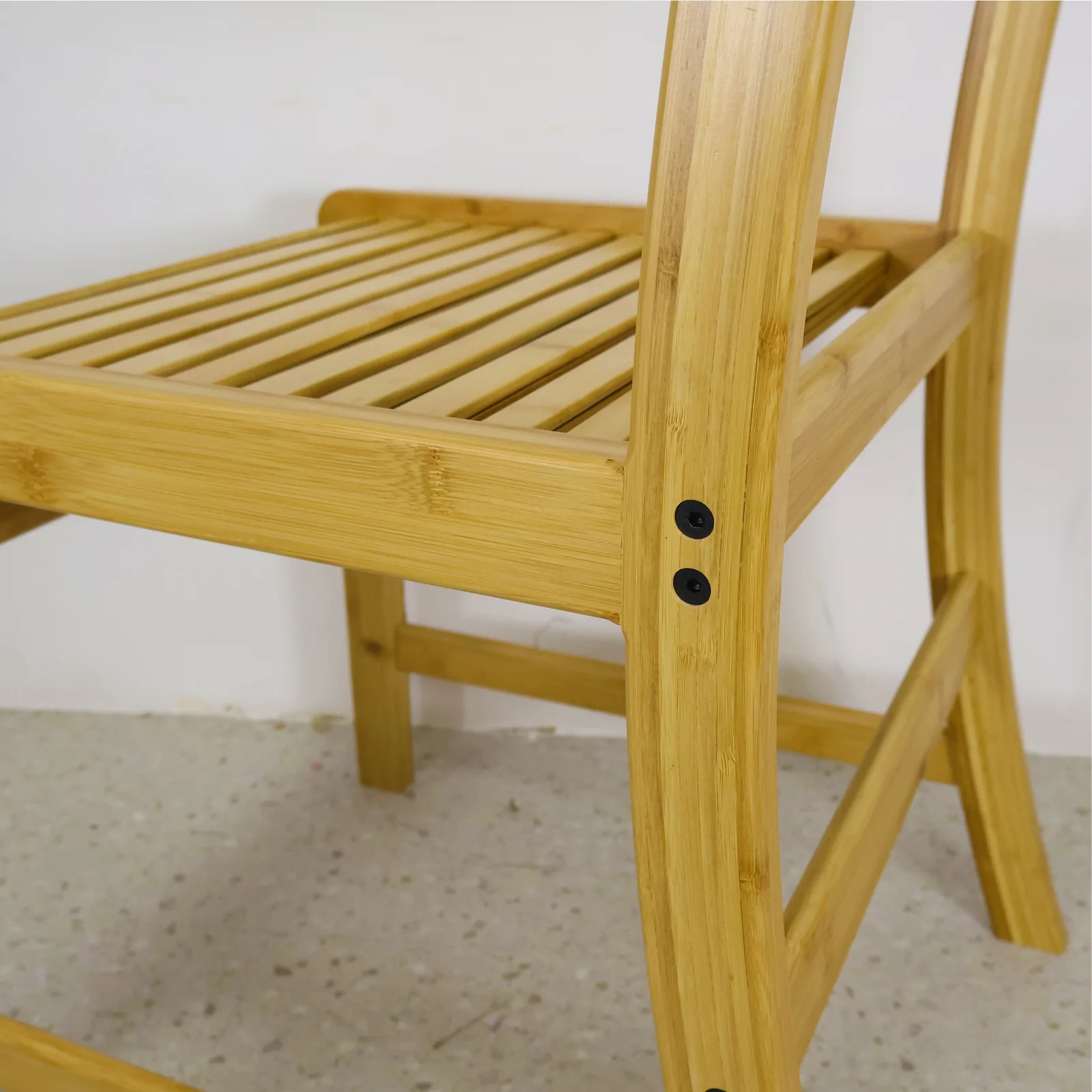 Close-up of the seat rail, leg joint, and visible fasteners on an adult bamboo chair.