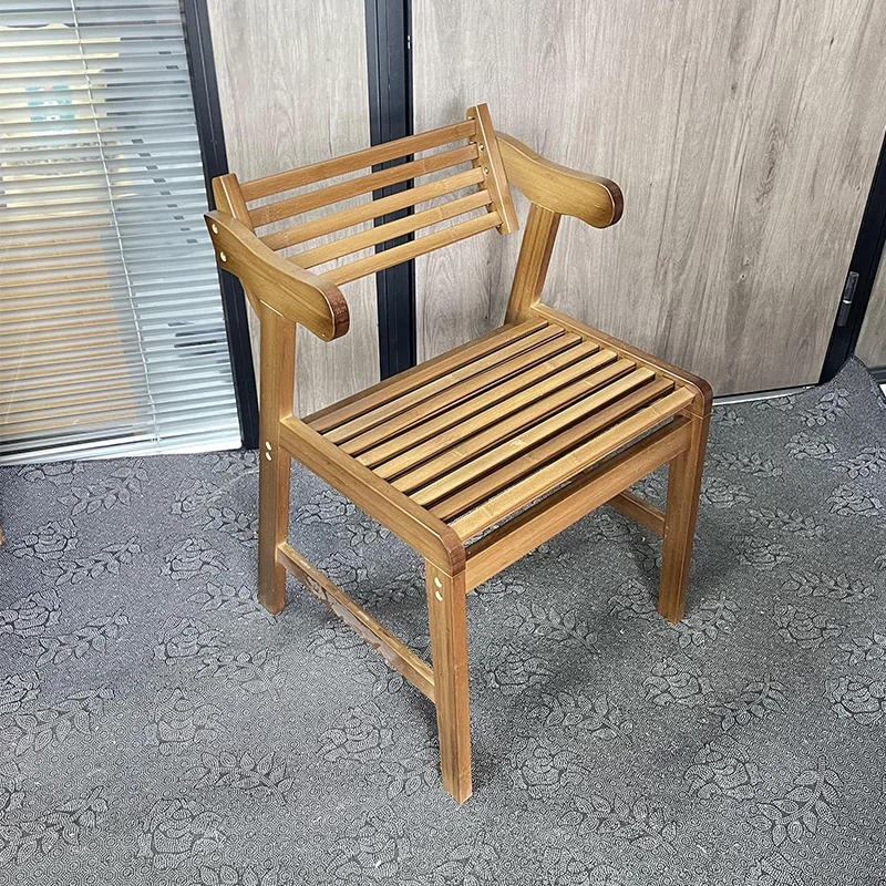 Three-quarter view of a bamboo armchair with curved armrests, a slatted seat and back, and a reinforced side stretcher.