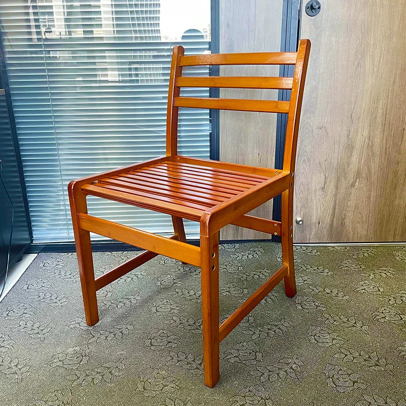 Three-quarter view of a ladder-back bamboo dining chair with a warm glossy finish.