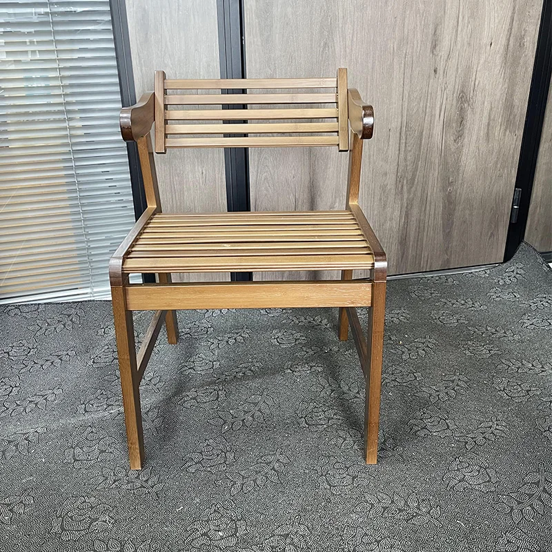 Front view of a warm brown bamboo armchair with a slatted seat, horizontal backrest, and gently curved arms.